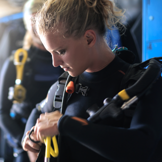 Scuba diving student checking equipment before completing the last dive of her course in Tulum
