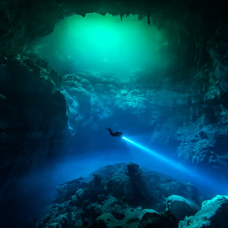 Light shines on diver at Cenote the Pit near Tulum