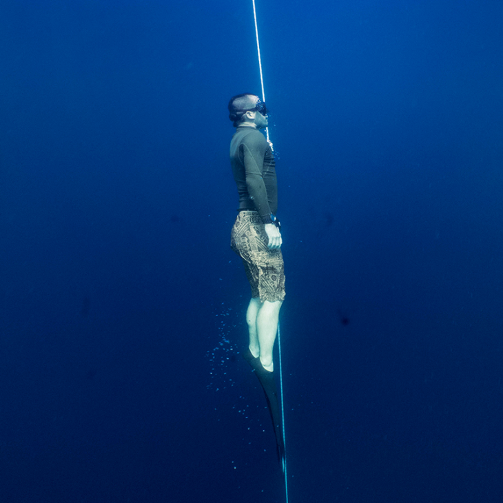 Freediver ascending from deep dive along the line.