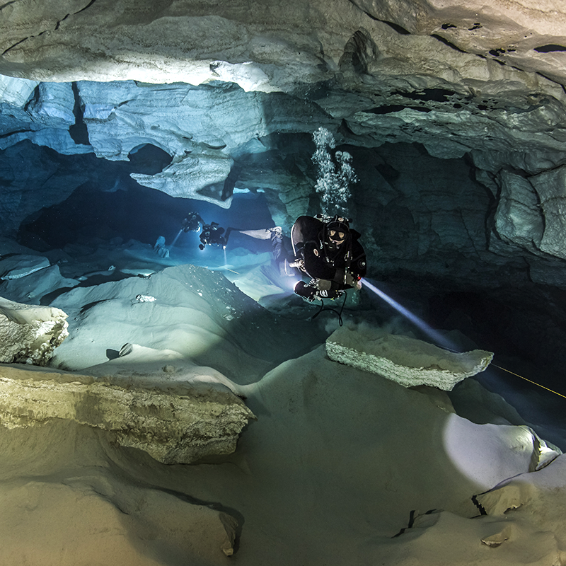 3 divers posing for a picture inside a cave in Tulum.