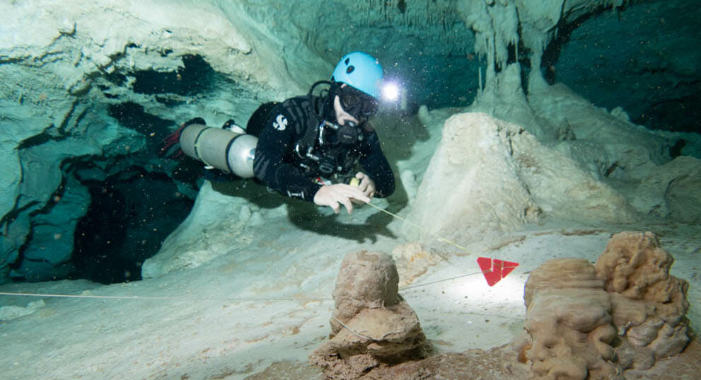 Cave diver picking up a jump line in a cenote near Playa del Carmen