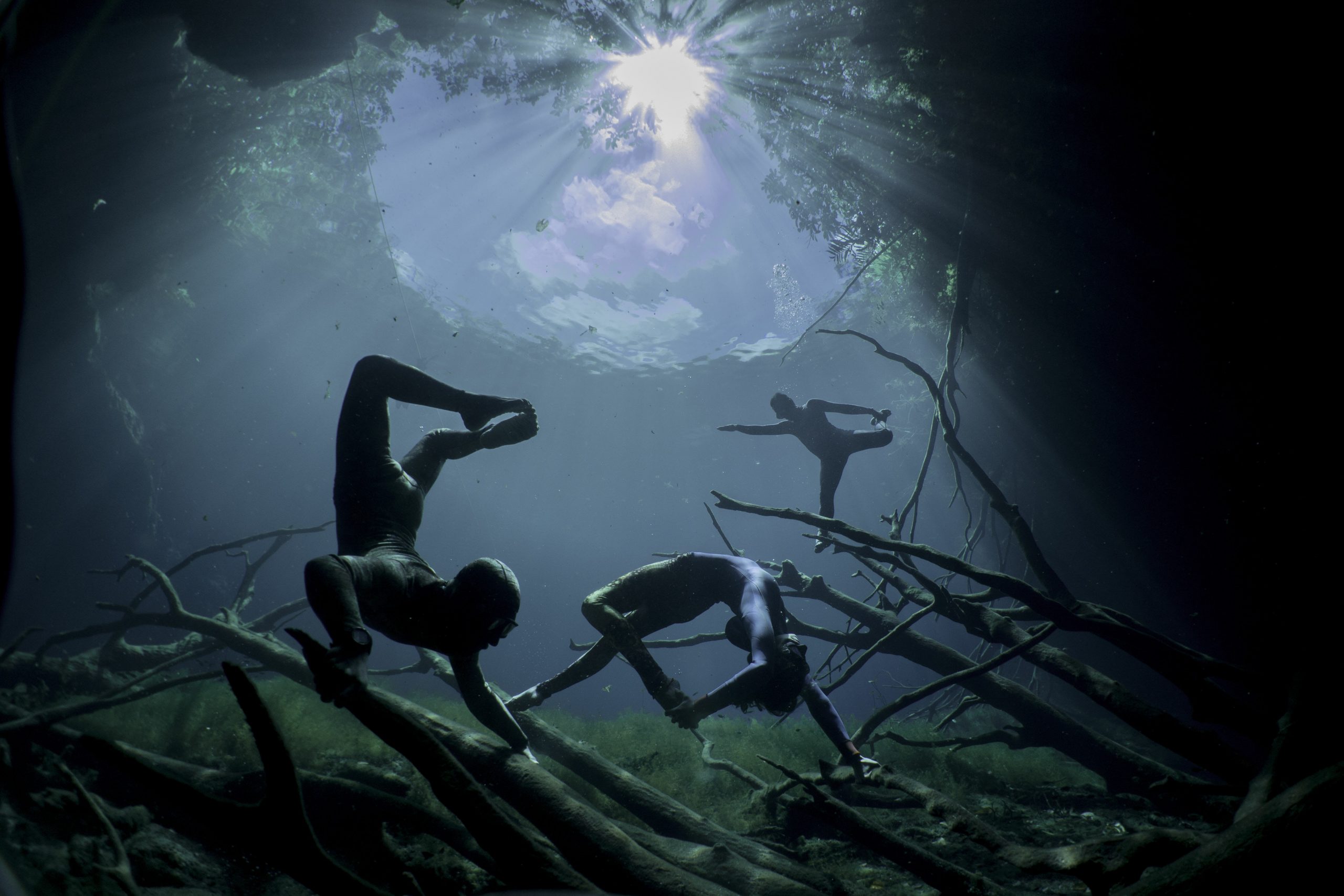 Freedivers in Yoga poses at Cenote Car Wash near Tulum